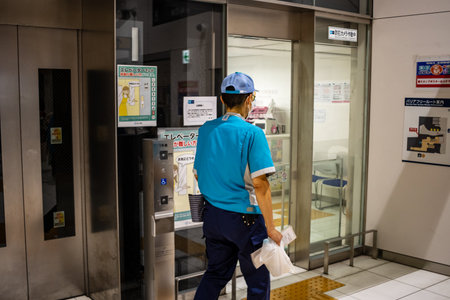 Tokyo, Japan, October 29, 2023: Delivery worker entering a building through automatic doorsのeditorial素材