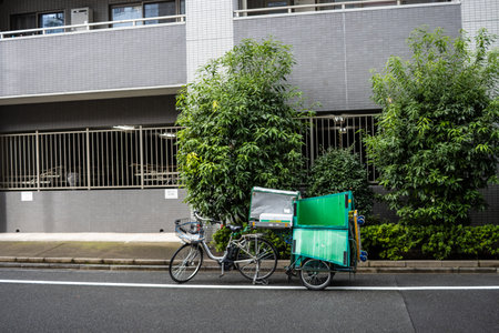 Tokyo, Japan, October 29, 2023: Delivery bicycle with green insulated box parked on city sidewalkのeditorial素材