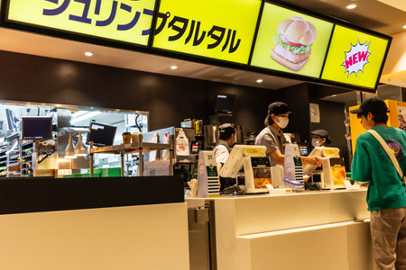 Tokyo, Japan, October 29, 2023: Patrons at the counter of a fast food restaurant with promotional signageのeditorial素材