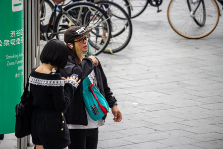 Tokyo, Japan, October 29, 2023: Couple in urban setting near designated smoking areaのeditorial素材