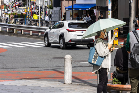 Tokyo, Japan, October 29, 2023: Pedestrian with Umbrella Waiting at Tokyo Crosswalkのeditorial素材