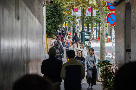 Tokyo, Japan, October 29, 2023: People Walking Through Shaded Alley in Busy Tokyo Areaのeditorial素材