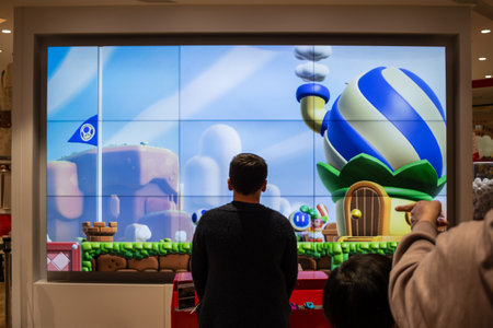 Tokyo, Japan, October 29, 2023: Onlookers watching a game demo on a large screen in a storeのeditorial素材