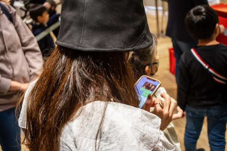 Tokyo, Japan, October 29, 2023: Young customer playing a handheld game in a crowded storeのeditorial素材
