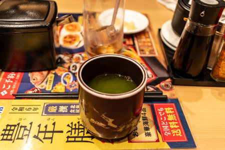 Tokyo, Japan, October 29, 2023: Close-up of a hot green tea cup on a restaurant table with condimentsのeditorial素材