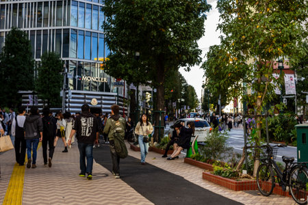Tokyo, Japan, October 29, 2023: Pedestrians walking on a tree-lined street near luxury retail shopsのeditorial素材