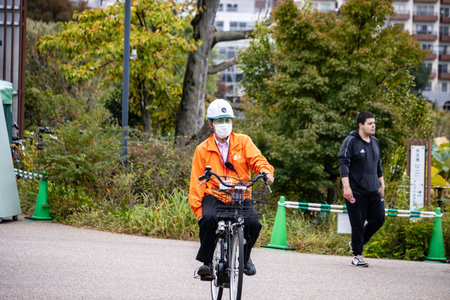 Tokyo, Japan, October 31, 2023: Postal Worker Delivering Mail on Bicycle in Tokyo