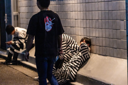 Tokyo, Japan, October 31, 2023: People in costume on a sidewalk at night, possibly post-eventのeditorial素材