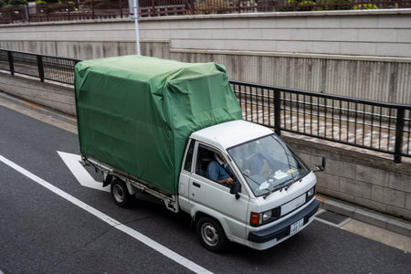 Tokyo, Japan, October 31, 2023: Small green truck driving on city highwayのeditorial素材