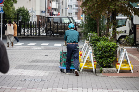 Tokyo, Japan, October 31, 2023: Worker in uniform preparing equipment on a city sidewalkのeditorial素材