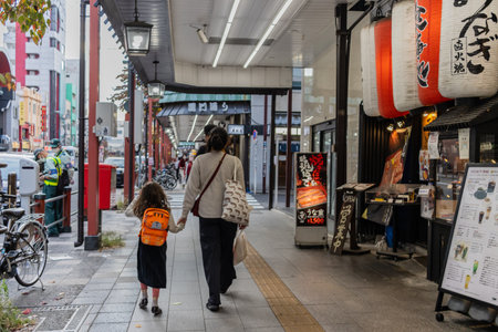 Tokyo, Japan, October 31, 2023: Adult and child walking past traditional restaurants and shops in the cityのeditorial素材