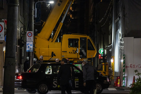 Tokyo, Japan, October 31, 2023: Nighttime city scene with a construction crane and workersのeditorial素材