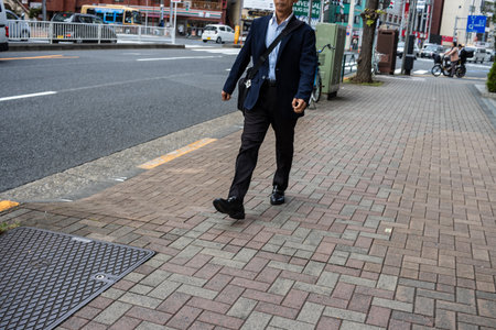 Tokyo, Japan, October 31, 2023: Businessman walking on the sidewalk in a busy city areaのeditorial素材