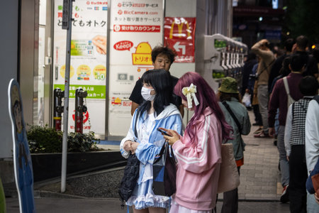 Tokyo, Japan, October 31, 2023: People in line at a city street in the evening with illuminated signsのeditorial素材