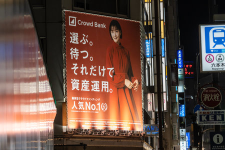 Tokyo, Japan, October 31, 2023: Outdoor advertising for Crowd Bank with a city nightscapeのeditorial素材