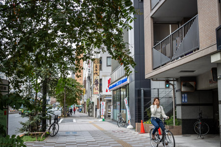 Tokyo, Japan, October 31, 2023: Woman cycling on a tree-lined Tokyo streetのeditorial素材