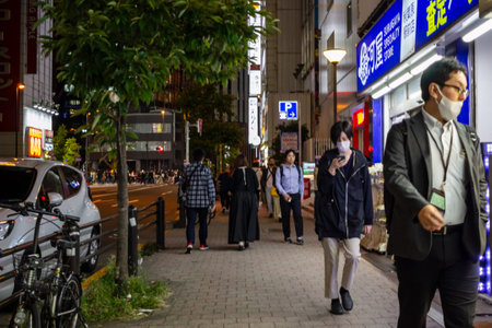 Tokyo, Japan, October 31, 2023: Pedestrians walking on a sidewalk at nightのeditorial素材
