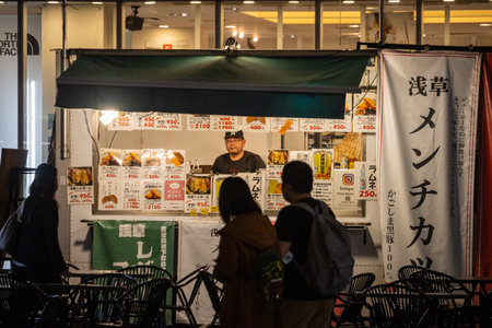 Tokyo, Japan, October 31, 2023: Customers at a street food stall at nightのeditorial素材