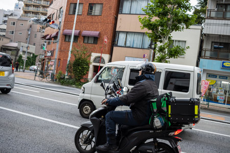 Tokyo, Japan, October 31, 2023: Delivery person on motorcycle on the streets of Tokyoのeditorial素材