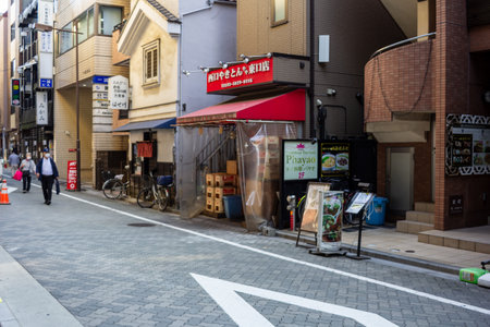 Tokyo, Japan, November 1, 2023: Pedestrians walking past small businesses on a quiet Tokyo streetのeditorial素材