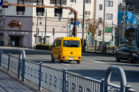 Tokyo, Japan, November 1, 2023: Yellow Delivery Truck Driving Across Bridge in Tokyo