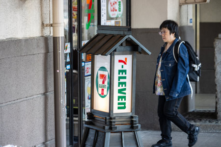 Tokyo, Japan, November 1, 2023: Pedestrian Passing by a 7-Eleven Store Signのeditorial素材