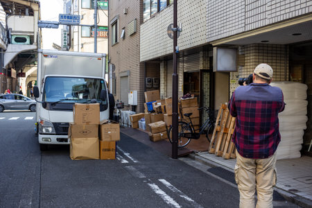 Tokyo, Japan, November 1, 2023: Worker Unloading Boxes in Alleywayのeditorial素材