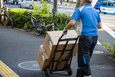 Tokyo, Japan, November 1, 2023: Delivery Man Pushing a Trolley with Cardboard Boxes in the Streetのeditorial素材