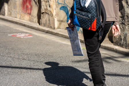 Tokyo, Japan, November 1, 2023: Person Walking on Sidewalk Carrying a Newspaper and Wearing a Crossbody Bagのeditorial素材