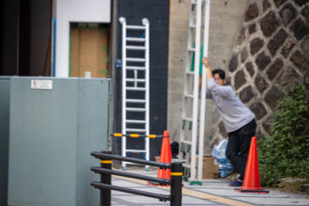 Tokyo, Japan, November 1, 2023: Man Setting Up a Ladder Outside a Buildingのeditorial素材