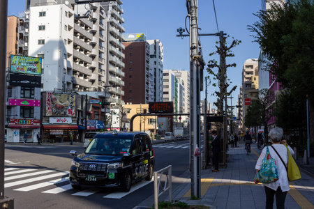 Tokyo, Japan, November 1, 2023: City Street Scene with Pedestrian and Colorful Taxiのeditorial素材