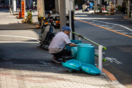 Tokyo, Japan, November 1, 2023: Worker Cleaning a Public Trash Can on the Streetのeditorial素材