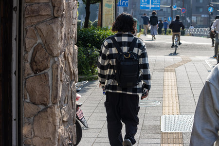 Tokyo, Japan, November 1, 2023: Man Walking Alongside a Road in Tokyoのeditorial素材
