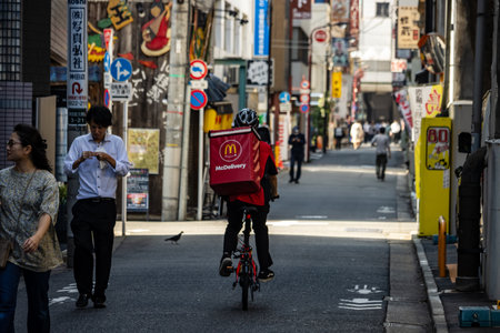 Tokyo, Japan, November 1, 2023: McDonald's Delivery Rider Cycling on a Busy Streetのeditorial素材