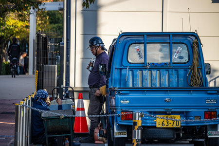 Tokyo, Japan, November 1, 2023: Worker Loading Equipment into a Blue Pickup Truckのeditorial素材
