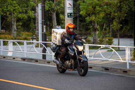 Tokyo, Japan, November 1, 2023: Delivery rider on a motorcycle crossing the bridgeのeditorial素材