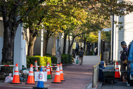 Tokyo, Japan, November 1, 2023: Pedestrian Pathway Lined with Trees and Safety Conesのeditorial素材