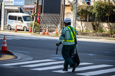 Tokyo, Japan, November 1, 2023: Traffic Controller in Safety Vest Directing Vehicles at a Construction Siteのeditorial素材