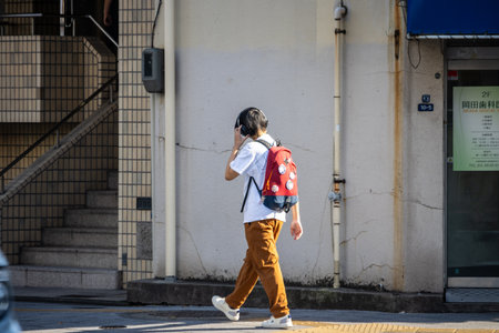 Tokyo, Japan, November 1, 2023: Woman walking on the sidewalk in Tokyo with a red backpackのeditorial素材