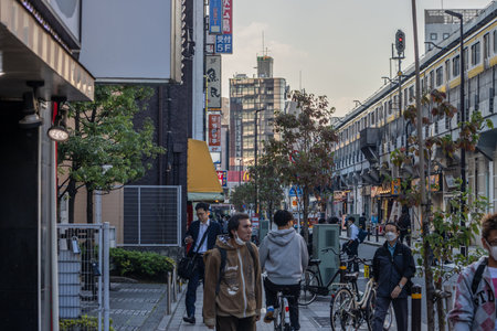 Tokyo, Japan, November 1, 2023: People walking along a tree-lined street in Tokyo during the day