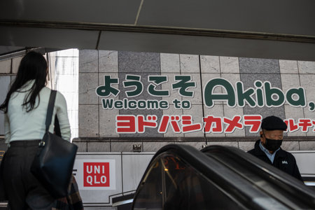 Tokyo, Japan, 1 November 2023: Welcome sign to Akihabara with people on escalator and Uniqlo...