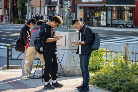 Tokyo, Japan, November 1, 2023: Young Men Using Smartphone on Sidewalkのeditorial素材