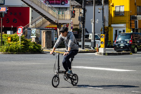 Tokyo, Japan, November 1, 2023: Man riding a folding bicycle on urban streetのeditorial素材
