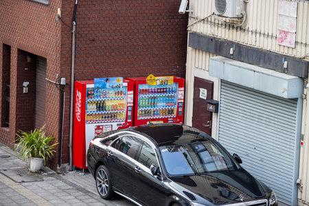 Tokyo, Japan, November 1, 2023: Parked Car in an Alley with Vending Machines and Red Brick Wallのeditorial素材