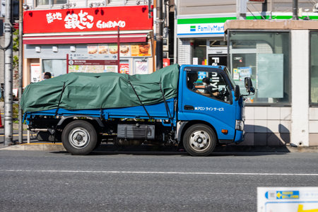 Tokyo, Japan, November 1, 2023: Blue truck passing by FamilyMart and Gindaco in Tokyoのeditorial素材