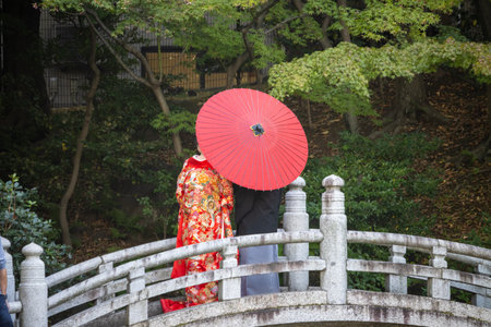 Tokyo, Japan, November 1, 2023: Traditional Japanese woman with red umbrella on bridgeのeditorial素材