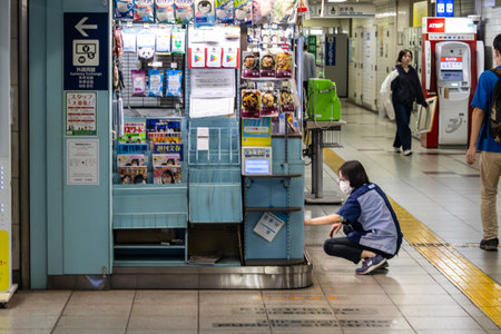 Tokyo, Japan, November 2, 2023: Worker Organizing Magazines at a Subway Station Kioskのeditorial素材