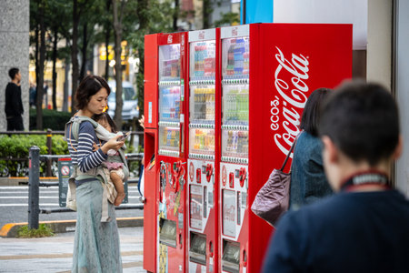 Tokyo, Japan, November 2, 2023: Woman Using Smartphone by Red Vending Machinesのeditorial素材