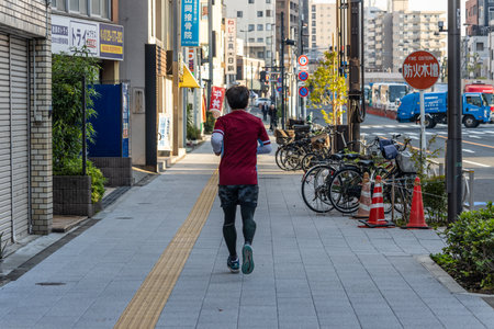 Tokyo, Japan, November 2, 2023: Person jogging on a city sidewalk with bicycles parked in the backgroundのeditorial素材