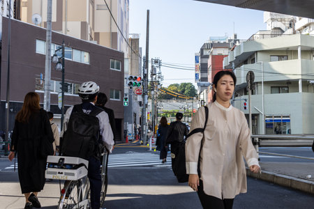 Tokyo, Japan, November 2, 2023: Daily Life Scene with Pedestrians and a Police Officer on Bicycle in Tokyo Streetのeditorial素材